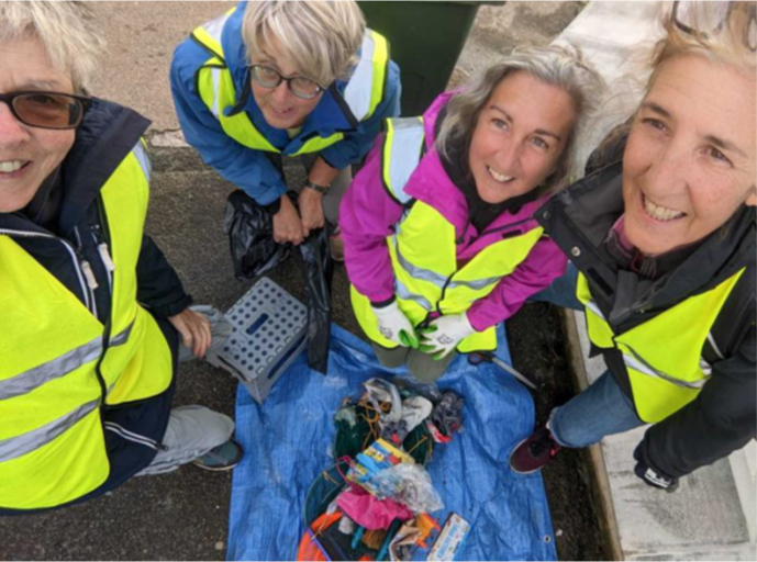 Smiling volunteers dressed in yellow tabards stand behind a large blue sack full of used crab lines